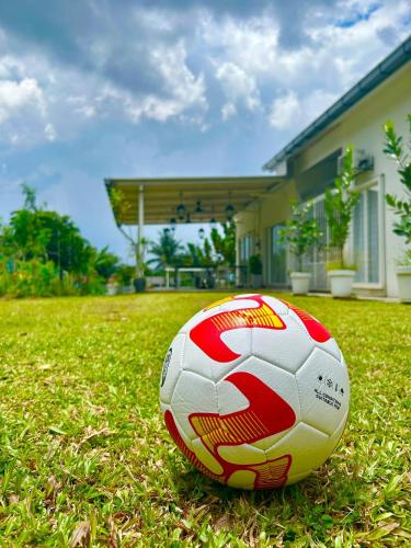 a soccer ball sitting on the grass in front of a house at Amicasa Homestay Seremban in Seremban