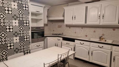 a kitchen with white cabinets and a table with chairs at Grande maison idéale réunions familiales in Nervieux