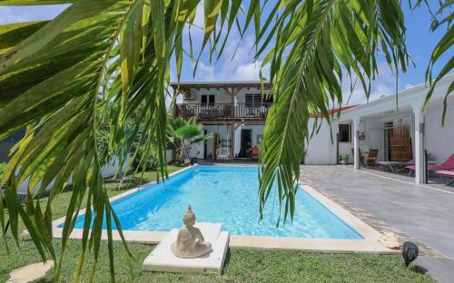 a villa with a swimming pool and a palm tree at Alpinia villa O'Mangos in Saint-François
