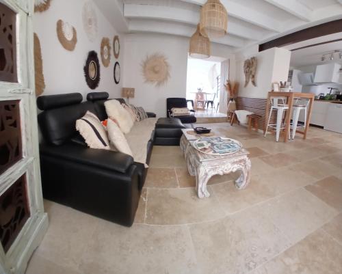 een woonkamer met een zwarte leren bank en een tafel bij La Bohème in Eyragues