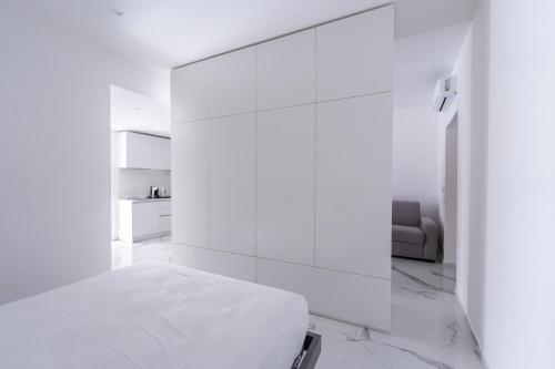 a white bedroom with a bed and a white wall at Alberti Apartments in Trapani