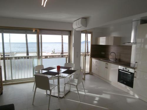 a kitchen with a table and chairs and a view of the ocean at Iberia Beach Front Sea in Juan-les-Pins