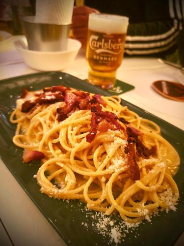 a green plate with pasta on a table with a glass of beer at Al vico art in Crosia