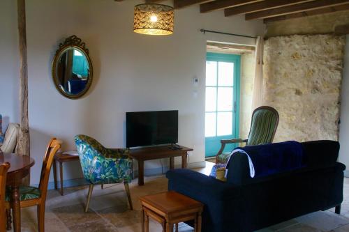 un salon avec un canapé bleu et une télévision dans l'établissement L'Écurie at Closerie Les Roches - Cozy 2 Bed Country Cottage, à Bouillé-Loretz