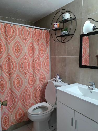 a bathroom with a toilet and a sink and a shower curtain at Stylish 2BR Prime Location Gated 24 7 Secure in Kingston