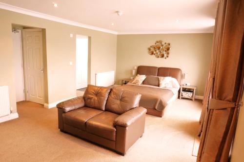a bedroom with a bed and a leather couch at shoreside inn in Shanklin