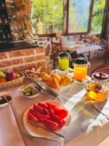 a table topped with plates of food and orange juice at Guesthouse Gjoni Theth in Theth