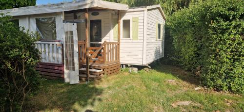 a small white cabin with a porch and a door at MOBIL HOME in Ivry-la-Bataille