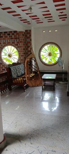 - un salon avec deux fenêtres et une table dans l'établissement Illam heritage home stay, à Trivandrum