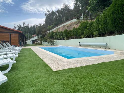a swimming pool in a yard with white chairs at Casa do Casal in Arouca