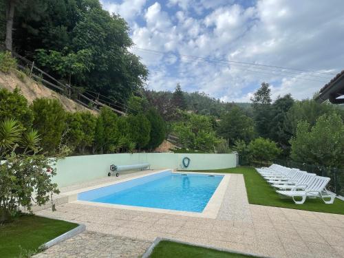 a swimming pool with white chairs and a swimming poolvisor at Casa do Casal in Arouca