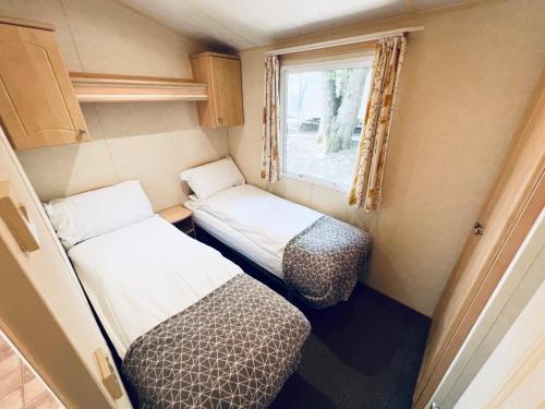 a small room with two beds and a window at 2 Bedroom Caravan GW39, Thorness Bay, Isle of Wight, Dog Friendly in Porchfield