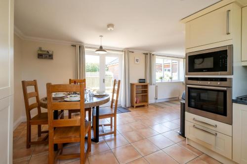 a kitchen and dining room with a table and chairs at 2 Hazelwood - 2 bedroom house near Aldeburgh & Snape Maltings - Aldeburgh Coastal Cottages in Aldringham
