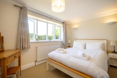 a bedroom with a bed with white sheets and a window at 2 Hazelwood - 2 bedroom house near Aldeburgh & Snape Maltings - Aldeburgh Coastal Cottages in Aldringham