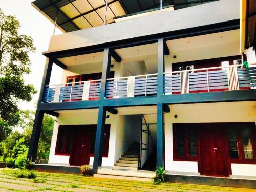 a large white building with a balcony on it at BOB Forest Stay in Batheri