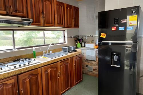 a kitchen with a black refrigerator and wooden cabinets at Casa con huerto orgánico. in Subachoque