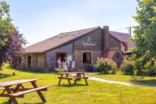 two picnic tables in front of a building at Au Cheval Noir in Quaëdypre