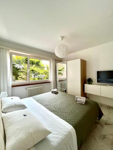 a bedroom with two beds and a tv and two windows at The Grand Vista - Lake View & Parking in Lugano