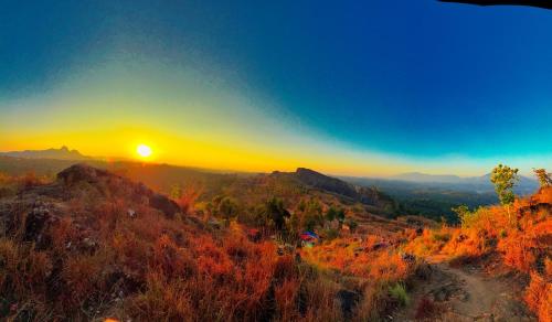 a sunset on a mountain with the sun setting at BOB Forest Stay in Batheri