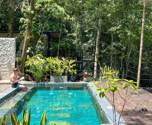 a man is sitting next to a swimming pool at Rincon de la Sierra Minca in Minca