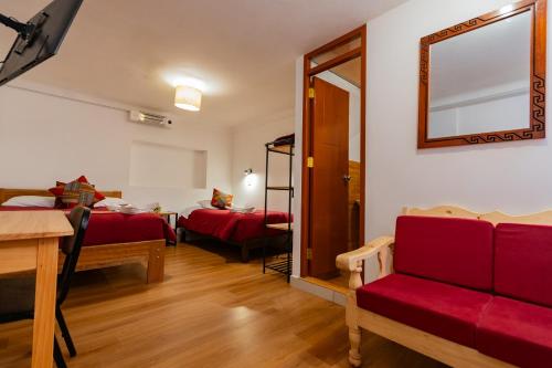 Habitación con 2 camas y sofá rojo. en Andes House Cusco, en Cusco