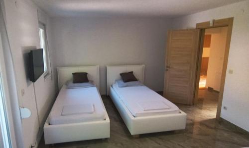 a room with two beds and a tv and a door at Villa Nature Sarajevo in Sarajevo