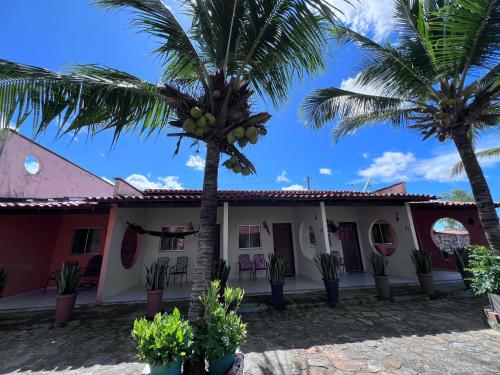 a house with palm trees in front of it at Pousada Chácara do Coqueiro in Barreirinhas
