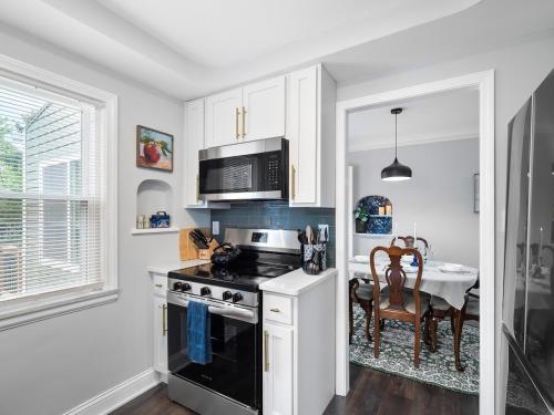 a kitchen with a stove and a dining room at Stylish Home - Game Room - Wet Bar - Sleeps 9 - Outdoor in South Euclid