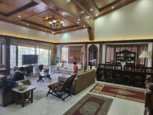 a living room with couches and a tv at Maskan Guest House in Murree