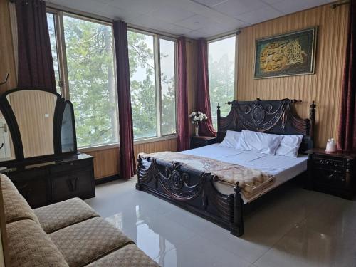 a bedroom with a bed and a couch and windows at Maskan Guest House in Murree