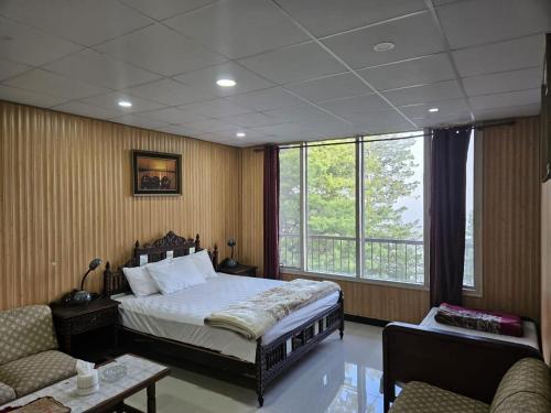 a bedroom with a bed and a couch and a window at Maskan Guest House in Murree