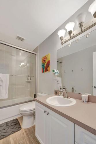 a bathroom with a sink and a toilet and a mirror at Sunny Waterfront Key Colony 3BR 3BA Villa w Dock in Key Colony Beach