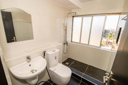 a bathroom with a toilet and a sink and a mirror at Crown Heights Apartment in Lagos
