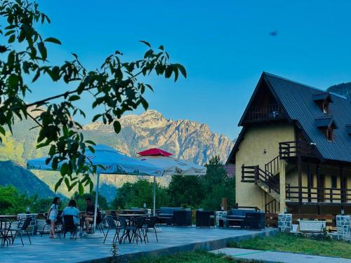 a patio with tables and umbrellas in front of a building at Guesthouse Gjoni Theth in Theth