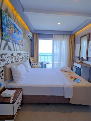 a large bedroom with a large bed and a table at KUPALA BEACH HOTEL in Büyükkeçeli