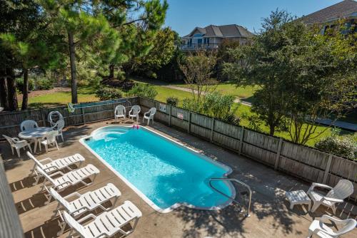 a swimming pool with chairs and a table and a table and chairs at Good Sun-Sations in Corolla