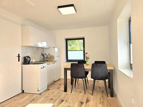 a kitchen with a table and two black chairs at Kompleks domków na Mazurach dla grupy 15 osobowej in Sędańsk