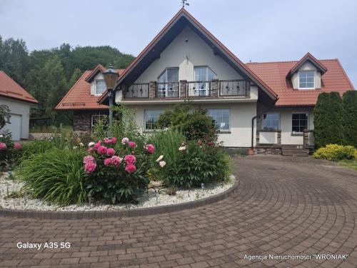 a house with a brick driveway with flowers in front at Sunny Hill Apartment in Smętowo Chmieleńskie