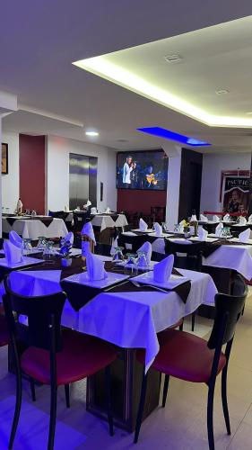 a dining room with tables and chairs and a screen at Hotel Leblanc Suites in Puerto La Cruz