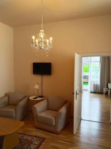 a living room with two chairs and a chandelier at Leier apartments in Piešťany