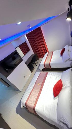 two beds with red pillows in a room at Hotel Leblanc Suites in Puerto La Cruz