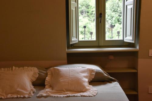 a bed with two pillows in front of a window at La Vecchia Scuola in Stifone
