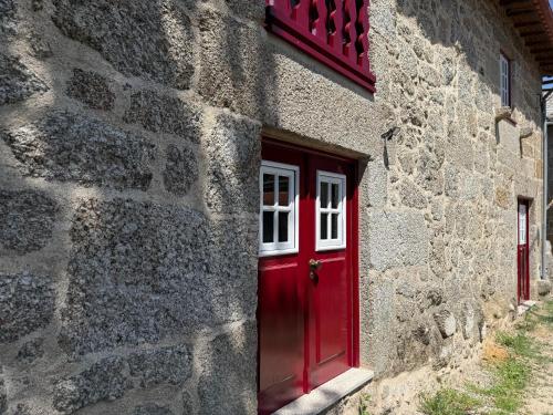 a red door on the side of a stone building at Refúgio Rural - Gerês in Terras de Bouro
