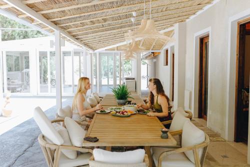 three women sitting at a table in a dining room at YONIK Farm - Detox retreat in nature in Miliou