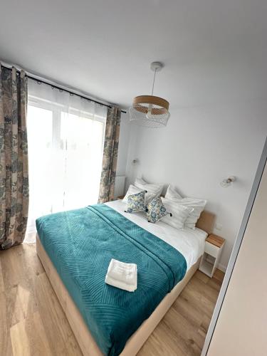 a bedroom with a bed with a blue blanket and a window at Dune & Sea in Ustronie Morskie