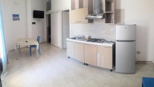 a kitchen with a white refrigerator and a table at Villa Bludea - Salento in Torre Lapillo