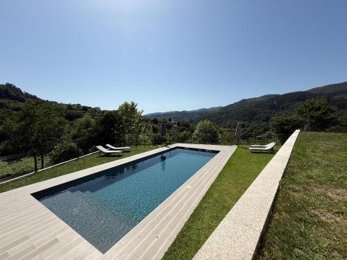 a swimming pool in a yard with two chairs at Refúgio Rural - Gerês in Terras de Bouro