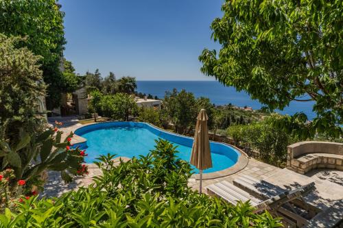 a swimming pool with an umbrella and a table and chairs at Castello degli Aranci Eco Resort in Reževići