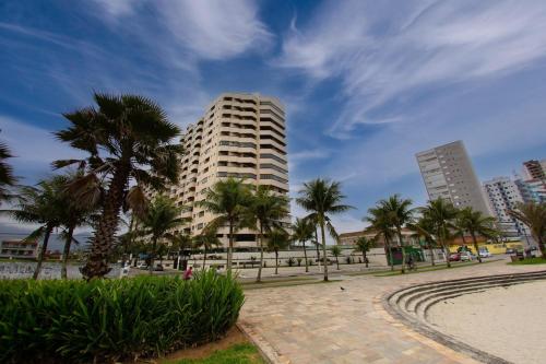 a tall building with palm trees in a park at Cobertura duplex com Jacuzzi e vista espetacular para a praia e a cidade in Praia Grande