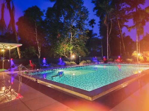 a swimming pool at night with people in it at Green Aura By BOB in Sultan Bathery